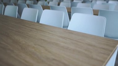 Okul kafeteryasında ahşap masalar ve beyaz sandalyeler düzgünce düzenlenmiş. Büyük masalar öğrencilerin rahat yemek yemesi için bolca yer sağlar.