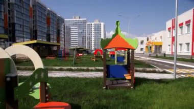 Anaokulunun bahçesinde çimenlik alana yerleştirilmiş güneş dolu oyun alanı. Anaokulu eğitim kurumu. Eğitim kurumlarının mimarisi