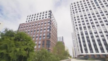 Modern yüksek ofis binalarıyla çevrili geniş bir yürüyüş yolu. Apartman binaları ve ağaçlar şehir merkezinin alçak açılı çekimini sembolize ediyor.