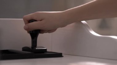 Kadın el işi sarmal not defterinin kapağına yakın çekimde pul yapıştırıyor. Kadın ofis çalışanı geri dönüşümlü not defterini işaretliyor. Evrak işi.