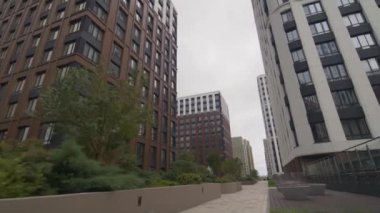 Yüksek binalarla çevrili çitlerle çevrili boş kaldırım. Şehir sokakları modern konut ve ofis yapılarıyla dolu.