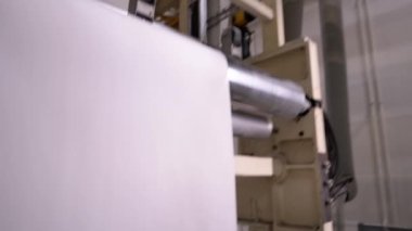 Fabrika atölyesindeki değirmen makinesiyle kurutulmuş uzun kağıt levha. Kağıt fabrikasında doku kurutma ekipmanları çalışıyor.