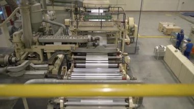 ALMATY, KAZAKHSTAN - 12 Temmuz 2024: Metal silindirli ve servis alanından kağıt levha görünümlü üretim hattı. Kağıt üretim tesisinde makine aracı otomatik olarak çalışır