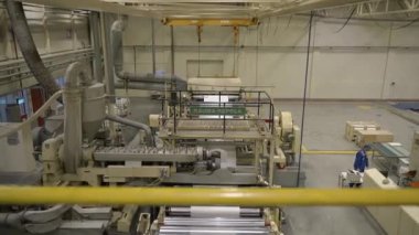 ALMATY, KAZAKHSTAN - 12 Temmuz 2024: Fabrika atölyesinde dönen makineler arasında geri dönüşümlü malzemelerin kağıt sayfası. Sanayi tesislerinde kağıt yapımında kullanılan ekipman