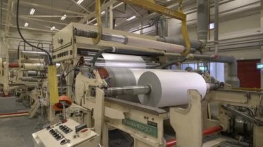 ALMATY, KAZAKHSTAN - 12 Temmuz 2024: Atölyedeki kağıt üretim hattının basın bölümünde dev metal variller. Makine aracı kağıt üretim tesisinde doku katmanı rulo