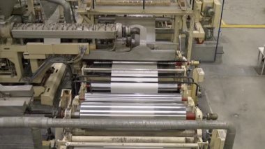 ALMATY, KAZAKHSTAN - 12 Temmuz 2024: Fabrika atölyesinde dönen tekerlekler arasında beyaz kağıt şerit. Otomatik makine aracı kağıt üretim endüstriyel tesislerinde çalışır