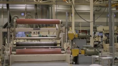 ALMATY, KAZAKHSTAN - 12 Temmuz 2024: Geniş fabrika atölyesinde dokuma kağıdı sarma ekipmanı. Makine kağıt imalat atölyesinde çalışıyor. Fabrikada modern teknoloji