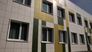 Renkli fayanslarla süslenmiş devlet anaokulu binası cephesi. Büyük pencereler güneş ışığını yansıtıyor yaz günü aydınlatma binası