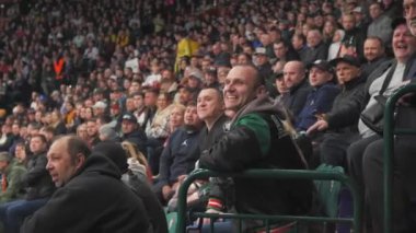 ALMATY, KAZAKHSTAN - 25 Mart 2024: hoşnutsuz izleyiciler hokey sahasına doğru bağırıyor. Şapkalı sarışın kadın ve orta yaşlı adam olumsuz duygularını jestlerle dile getiriyorlar.