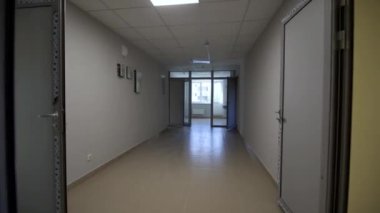 Ofis binasının boş koridoru lambalarla aydınlatılmış. Modern hastanenin cam kapıları olan bir koridor. İş merkezi yenileme ve iç tasarım