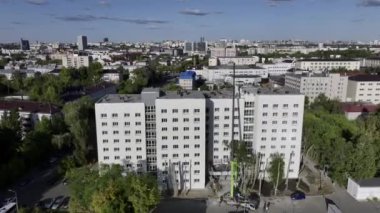 Şehir manzarasına karşı yenilenen ofis binaları. Kamyon vinci, yüksek ağaçlarla çevrili, gökyüzü manzaralı bir binada çalışıyor.