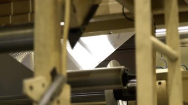 Alüminyum folyo, otomatik üretim hattında geri dönüşümlü malzeme imalatı. Parlak metal levha, atölyede dönen tekerleklerle taşınır.