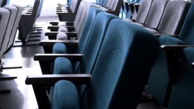 Yumuşak kumaşla döşenmiş rahat koltuklar. Konferans salonundaki izleyiciler için görünürlüğü arttırmak üzere tasarlanmış sandalyeler.