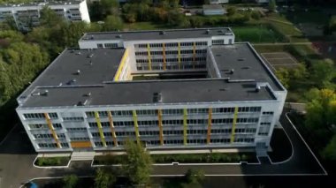 Etrafı yerleşim yerleriyle çevrili çok katlı okul binası. Okulun bölgesi özenle korunan spor alanlarını içeriyor