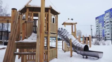 Kışlık çocukların oyun parkında metal kaydırağıyla ahşap labirent. Karlı şehir parkındaki küçük çocuklar için eğlenceli bir eğlence. Oyun oynamak için halka açık bir yer
