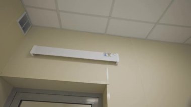 Çocuk hastanesinde cam kapının üstüne takılı uzun bir ultraviyole lamba. Tıbbi tesisler için sterilizasyon fonksiyonu olan modern aydınlatma çözeltisi