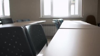 Boş sınıflardaki ahşap öğrenci masasının yanındaki sandalyeler. Okul binasının basit mobilyaları. Eğitim tesisi malzemeleri