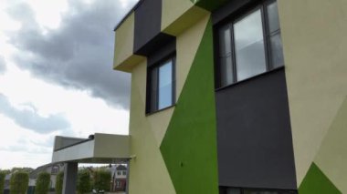 Bulutlu gökyüzünün altında okul binası cephesinde renkli geometrik desen. Kentsel eğitim merkezinin modern mimari tarzı. Sokak dekoru