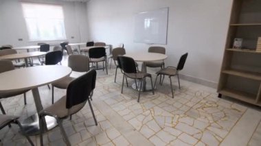 Çalışma odası, masalar, sandalyeler ve projeksiyon ekranı. Modern okul çevresi öğrenciler için rahat mobilyalarla çevrili. İç tasarım