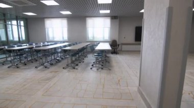 Sınıftaki büyük pencerelerin yanındaki öğrenci masaları ve koltukları. Cam duvarlı bir eğitim merkezi. Okulun iç mimari tarzını yeniledim