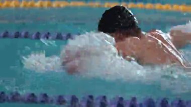 ALMATY, KAZAKHSTAN - 25 Ağustos 2024: Kelebek yüzücünün elleri hızını korumak için hızla hareket ediyor. Sporcu, suda kararlılıkla ilerler. Yüzücü zaferi garantilemeye kararlı