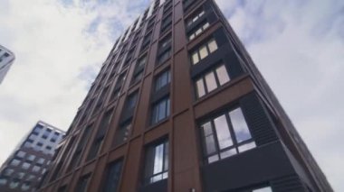 Şehir merkezinde parlayan yüzüyle gökyüzüne yükselen ticari bir bina. Cam dış görünüşlü ofis binaları şehir merkezinde düşük açılı çekimde duruyor.
