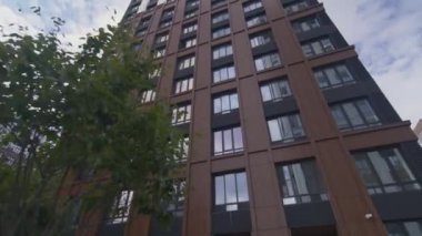 Modern ofis binası pencerelere bulutlu gökyüzünü yansıtır. İş merkezinde cam ön cephe alçak açılı minimalist dış cephe var.