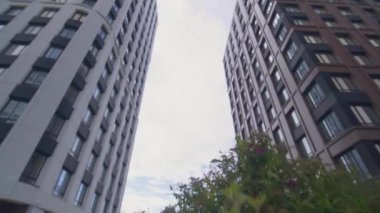 Şehir merkezinde aynalı pencereleri olan ticari binalar var. Yüksek katlı ofis binalarının cam cepheleri, alçak açılı bulutları yansıtan gökyüzüne yükselir.