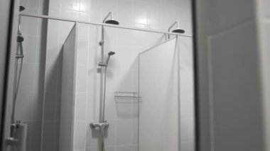 Ayrı duş kabinlerindeki farklı boyutlarda metal başlıklar. Spor kulübünde kişisel hijyen malzemeleri. Vücut yıkama odası.
