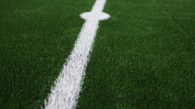Kapalı alandaki futbol sahası çimlerinin üzerinde beyaz işaretler var. Yumuşak, yapay ot düşüşün etkisini en aza indirir ve yaralanma riskini azaltır.