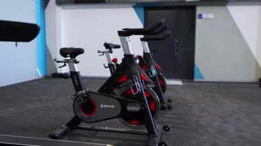 ALMATY, KAZAKHSTAN - 20 Mart 2024: Geniş pencereli modern spor salonunda bisiklet makinesi. Koltukla donatılmış spor bisikleti ve kaymayı önlemek için lastik tutamaklar.