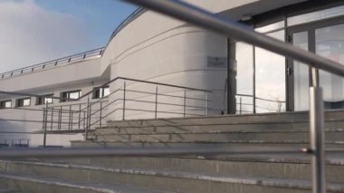 Enstitüye girişte koyu basamaklarla çerçevelenmiş parlak cam kapılar yer alıyor. Kış güneşi kar ve modern giriş arasında keskin bir kontrastlık yaratır.