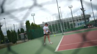 ALMATY, KAZAKHSTAN - 19 Ağustos 2024: Kadın tenisçi hızlı ve isabetli servis yapıyor. Deneyimli sporcu kadın spor kıyafetleri içinde raket sallıyor ve tenis topuna vuruyor.