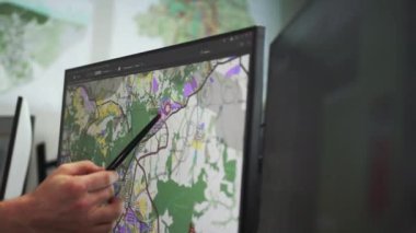 Adam, planlanan inşaat alanı için ayrılmış dijital haritada stil bölgesini gösteriyor. Erkek mühendis ofiste proje sunuyor