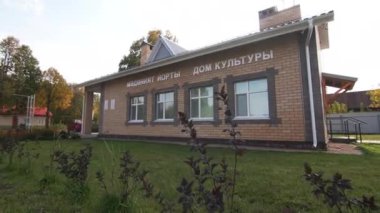 Parlak çimenler yenilenmiş Kültür Evi 'ni çevreledi. Yoğun yeşilliklerle çevrili güneş ışığı altında bina pencerelere yansıyan berrak gökyüzü