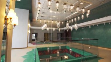 Sanat eseri, kırılgan cam ve parlak lambaların kombinasyonunu gösteren tiyatro lobisini dekore ediyor. Bir dizi asılı fener dizisi olan modern tasarım