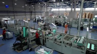 Posa ve kağıt endüstrisi kuruluşunda çalışan makinelerle atölye çalışması. Şirket çalışanları özel mekanizmaları çalıştıran makinelerin yanında dururlar.