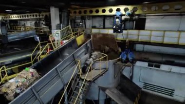 ALMATY, KAZAKHSTAN - 24 Eylül 2024: Eski atık kağıt materyali geri dönüşüm ekipmanlarına aktarılır. Endüstriyel makine, geri dönüşümlü kağıt balyaları, kıvrılmış karton üretiyor.