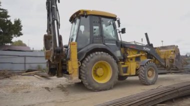 ALMATY, KAZAKHSTAN - Haziran 04 2024: Kazıcı inşaat alanı boyunca istiflenmiş metal kirişler arasında hareket eder. Yapının temelini oluşturmak için ağır makineler kullanılıyor