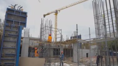 ALMATY, KAZAKHSTAN - Haziran 04 2024: Kask takan işçiler açık havada köprü iskeleleri için metal çerçeveler kuruyorlar. Üstgeçit köprüsünün elle montajı. Yaya köprüsü oluşturulması