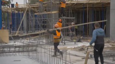 ALMATY, KAZAKHSTAN - 4 Haziran 2024: miğfer ve üniforma giyen inşaatçı inşaat alanından demir kiriş taşıyor. Köprü ulaşım arayüzünün inşaatı