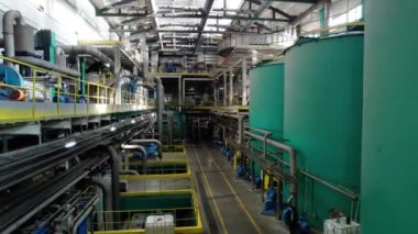 Mukavva üretim tesisleri olan geniş bir fabrika salonu. Mekanizmalar kağıt hamurunun tamamlanmış materyale dönüşmesini sağlar.