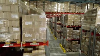 İçinde paketlenmiş ürünlerin olduğu rafların olduğu karton fabrika deposu. Salon, kamyonlara ve taşımacılığa daha fazla yük yüklenmesi için malzeme depoluyor