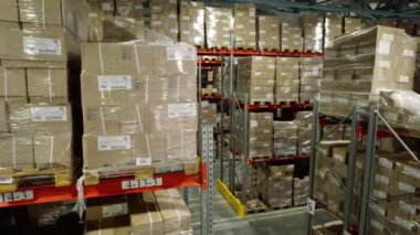 Karton fabrika deposunda bitmiş ürünlerle dolu raflar arasında bir koridor. Binada sanayi taşımacılığına daha fazla yük yüklenmesi için malzemeler yer alıyor