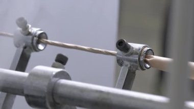 Büyük fabrika atölyesindeki makinede karton tüp oluşturuyorlar. Özel küçük silindirler ince maddenin son şeklinin oluşturulmasını sağlar