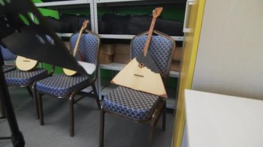 Kültür Evi 'nin ambarında bulunan Balalaikalar. Müzisyenlerin konforu için sandalye ve kürsülerle desteklenmiş kompozisyon