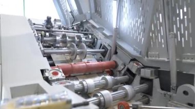 Büyük fabrika atölyesinde kağıt ağı germek için patenler. Cihazın dönen parçaları torba oluşturmak için malzeme seviyelendirme sağlar