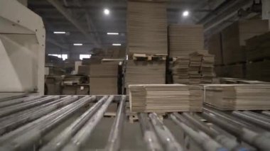 Taşıyıcı katlanmış alışveriş torbalarını rulo kullanarak taşıyor. Mekanizmanın etkin dönen parçaları malzeme teslimatını ambalaj alanına sağlar