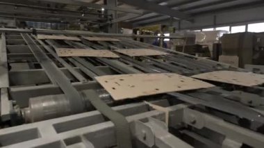 Taşıyıcı fabrika atölyesinde düz karton malzeme taşıyor. Ekipman, oluşturulan ürünü kağıt torba oluşturmak için işlemin bir sonraki aşamasına taşır