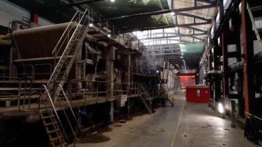 Endüstriyel ekipmanlı mukavva fabrikasının geniş bir atölyesi. Hall hammadde biçiminde kağıt işleme mekanizmaları içerir